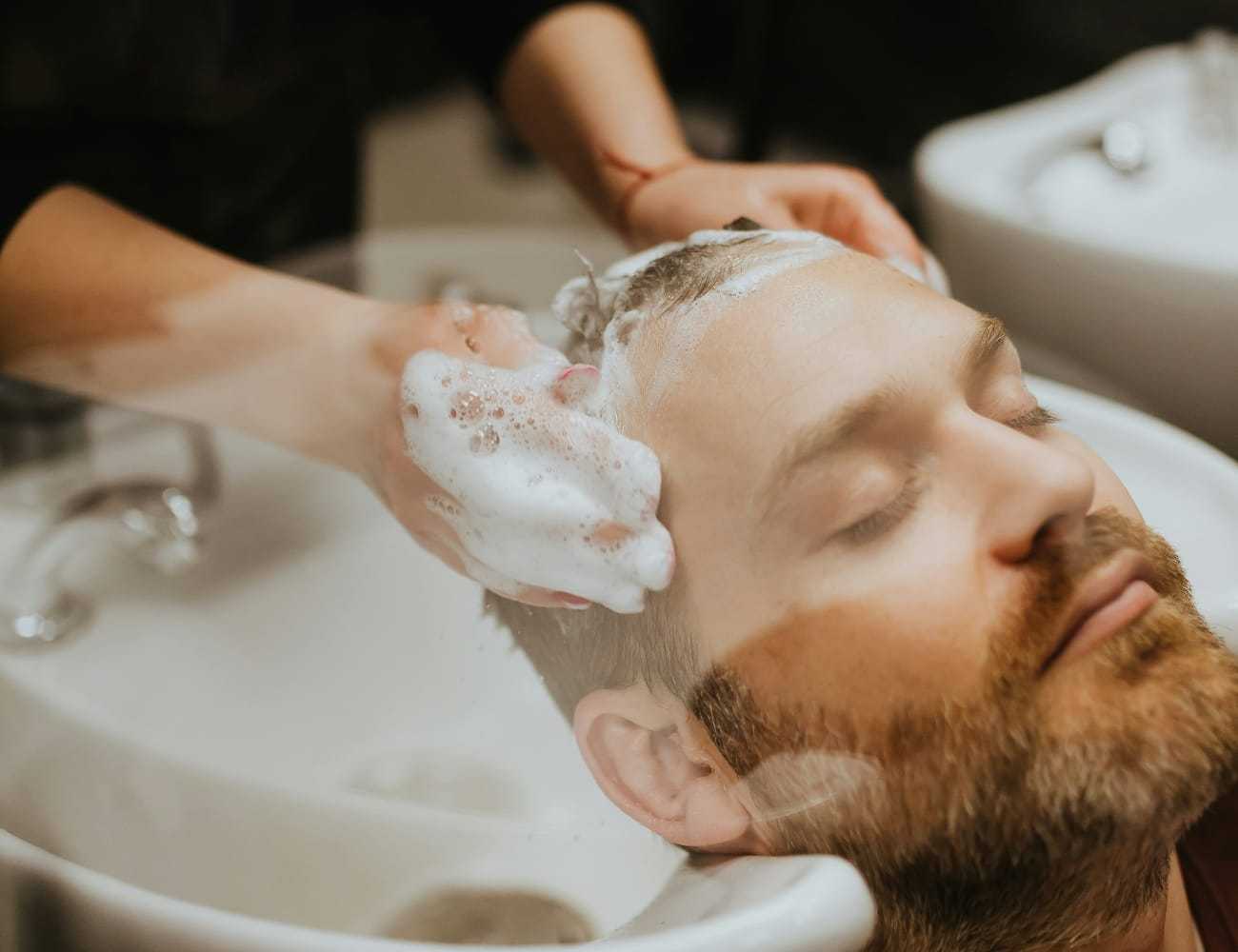Man relaxing while getting hair washed at a salon sink.